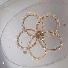 ヴォヤージュ　ドゥ　ルミエール北谷リゾートの画像｜挙式会場の天井につるされた花形のシャンデリア